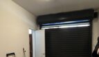 Garage mit schwarzem Rolltor, Seiteneingang, Fluoreszenzlicht und Betonboden im Stadthaus Artà