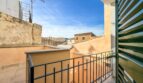 Balkon mit schwarzem Eisengeländer und grünen Holzläden, Blick auf Dächer in Felanitx