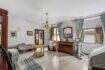 Living room with a chandelier, wooden dresser, mirror, and green curtains in a house in Felanitx