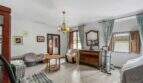 Living room with a chandelier, wooden dresser, mirror, and green curtains in a house in Felanitx