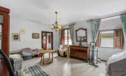 Wohnzimmer mit Kronleuchter, Holzkommode, Spiegel und grünen Vorhängen in Haus in Felanitx