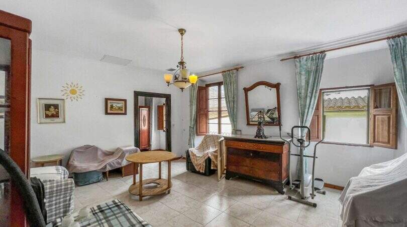 Living room with a chandelier, wooden dresser, mirror, and green curtains in a house in Felanitx