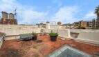 Rooftop terrace with terracotta tiles, plants, and a glass roof panel, overlooking neighboring buildings in Felanitx