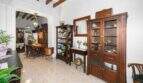 Living room with exposed wooden beams, wooden display cabinets, and a passageway to the dining room in a charming house in Felanitx