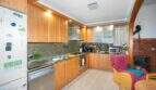Kitchen with wood cabinet fronts, granite countertops, and built-in appliances, and an adjoining living area with a wood-burning stove in Felanitx