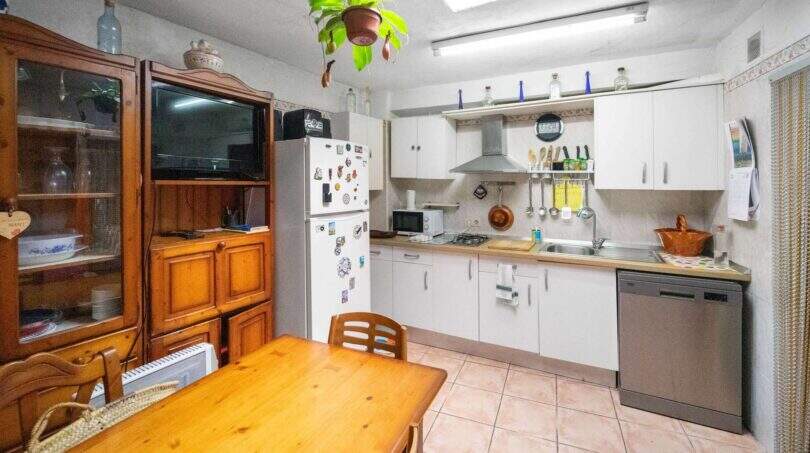Kitchen-living room with a wooden table, white built-in cabinets, a refrigerator, and a dishwasher in the house in Felanitx