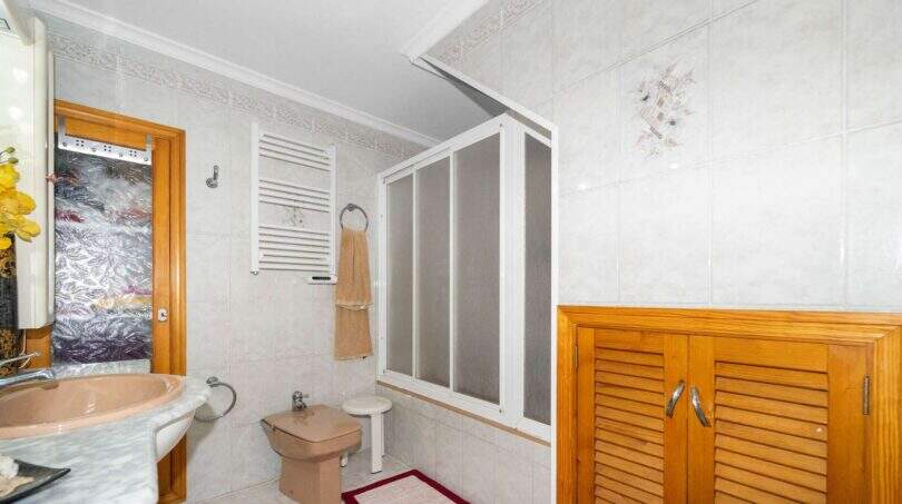 Bright bathroom with a shower stall, bidet, wooden cabinet, and white tiles in the house in Felanitx.