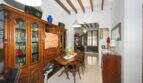 Dining room with a wooden beam ceiling, an antique bookcase, and a round dining table in a house in Felanitx