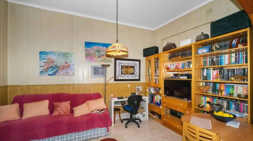 Living room with a red sofa, bookshelf, TV, and Tiffany pendant lamp in a charming house in Felanitx
