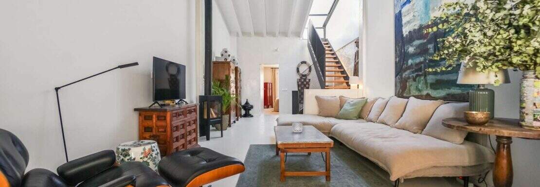 Helles Wohnzimmer mit Eames-Lounge-Chair, Leinensofa, moderner Kunst und hohen Decken im Stadthaus Capdepera