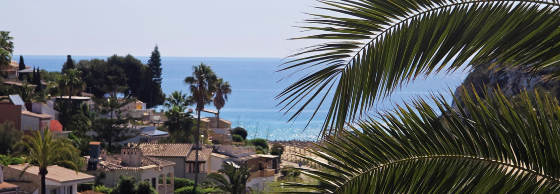 Panoramablick auf mediterrane Villen, Palmen und blaues Meer in Porto Cristo Novo.