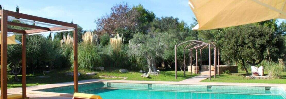 Poolbereich der Natursteinfinca in Canyamel mit Sonnenliegen, Pergola und gepflegtem Garten