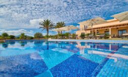 Großer Außenpool mit Mosaikfliesen, Liegestühlen und Sonnenschirmen vor mediterraner Finca in Portocolom