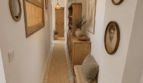 Langer heller Flur mit Natursteinfliesen, Sisalteppich, Holzmöbeln und Rattanlampe in Wohnung Porto Cristo
