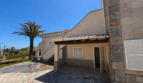 Outdoor area of a Majorcan villa in Manacor with covered entrance, natural stone cladding and palm tree.
