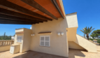 Covered rooftop terrace of the Majorcan villa with wooden beams, terracotta roof and palm tree view under blue sky.