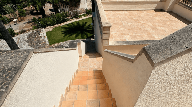 Terrace stairs with sandstone tiles, balustrade and sea view of a Majorcan villa in Manacor