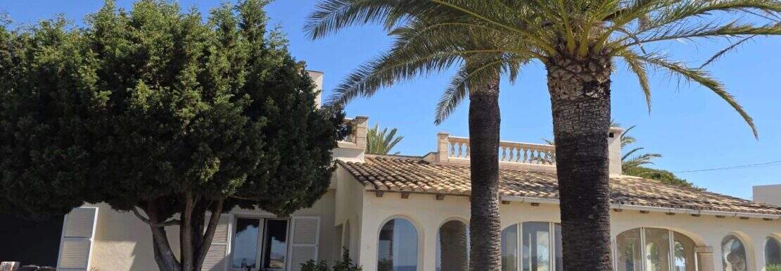 Außenansicht Villa Cala Murada mit Palmengarten, Bogenfenstern und mediterranem Terrakotta-Dach