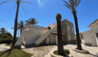 Exterior view of a Majorcan villa in Manacor with palms, stone paving, white façade and external staircase to the roof terrace.