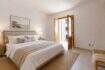 Helles Schlafzimmer der Maisonette in Porto Cristo mit Doppelbett, Holzmöbeln und Balkonzugang zum Meer.