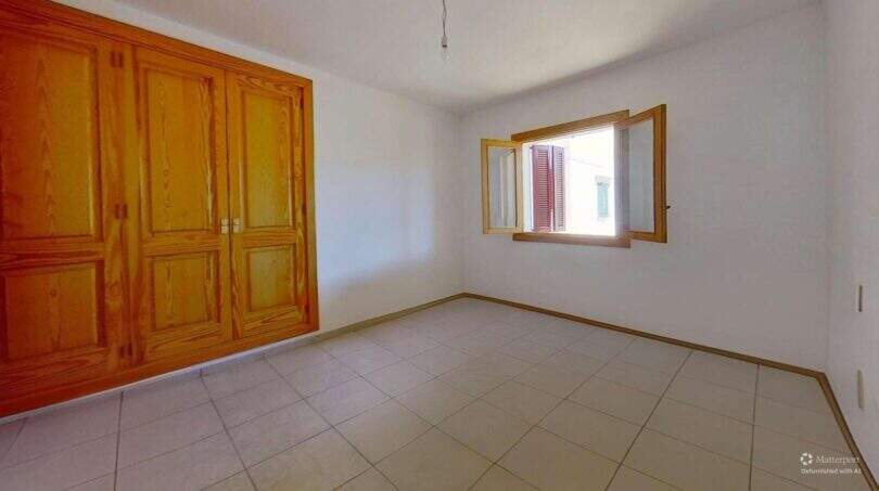 Helles Schlafzimmer der Maisonette in Porto Cristo mit Einbauschrank aus Holz und Fenster zum Innenhof