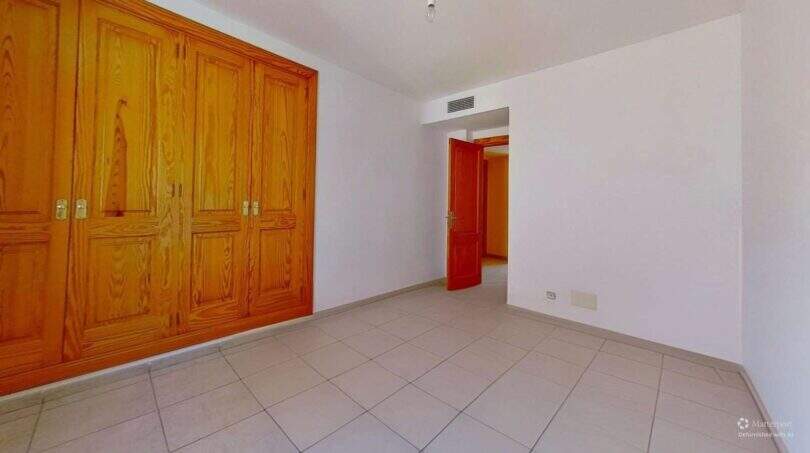 Helles Schlafzimmer der Maisonette in Porto Cristo mit großem Holzeinbauschrank und roter Tür