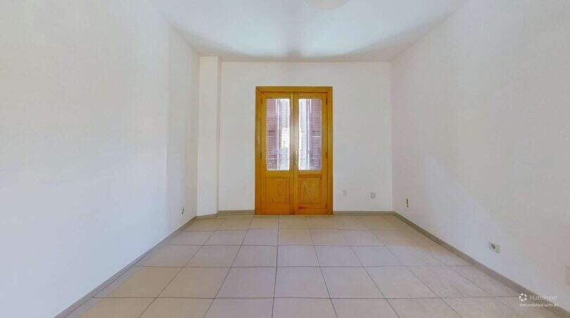Leerer heller Wohnraum mit Fliesenboden und zweiflügeliger Holztür mit Fensterläden in Maisonette Porto Cristo