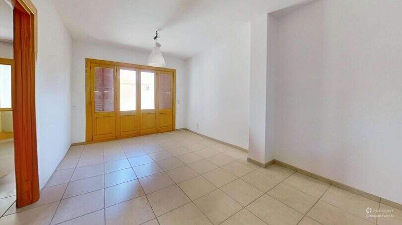 Helles, leeres Wohnzimmer mit Fliesenboden und Holzfenstertüren in Maisonette-Wohnung, Porto Cristo