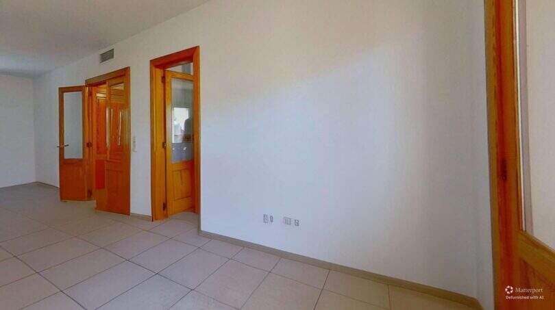 Leerer Flur der Maisonette in Porto Cristo mit Fliesenböden, weißen Wänden und drei Holztüren mit Glasfenstern