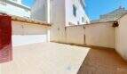 Sonniger Innenhof mit Terrakottafliesen, Wandleuchten und roter Holztür in Maisonette Porto Cristo