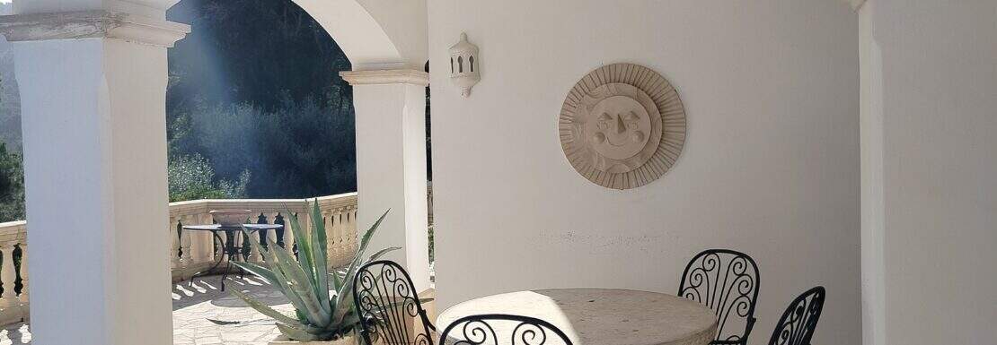 Überdachte Terrasse der Finca Felanitx mit Natursteinboden, Schmiedeeisen-Sitzgruppe und Rundbögen
