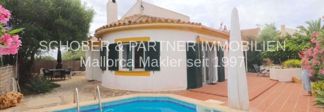 Chalet in Cala Murada: Außenansicht mit blauem Pool, weißer Rundvilla, Terrasse und mediterranem Garten.