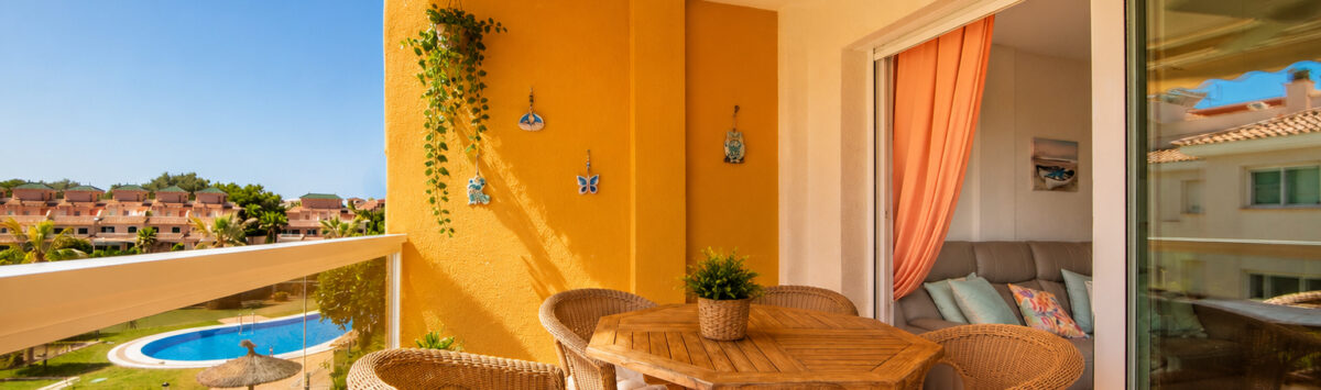 Sonnige Terrasse der Wohnung in Cales de Mallorca mit Rattanmöbeln und Blick auf den Pool