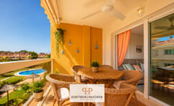 Sonnige Terrasse der Wohnung in Cales de Mallorca mit Rattanmöbeln und Blick auf den Pool