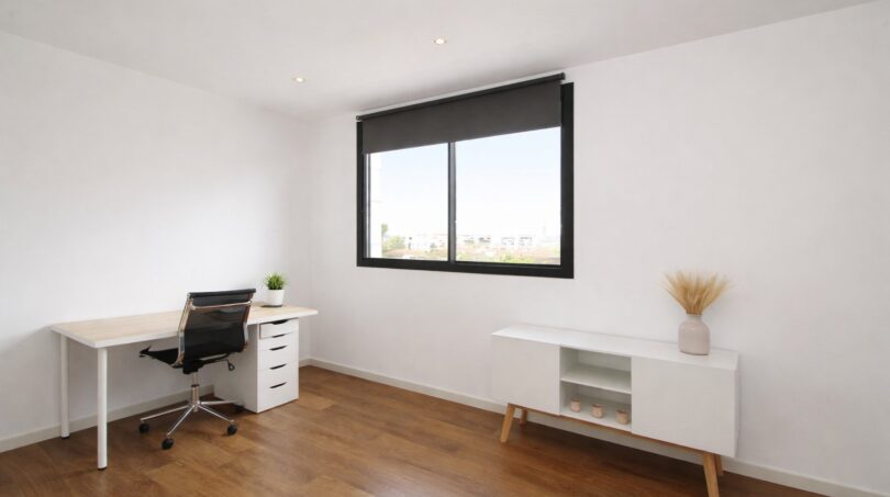 Modernes Arbeitszimmer mit Holzboden, Schreibtisch, ergonomischem Stuhl und Fenster mit Stadtblick in Palma