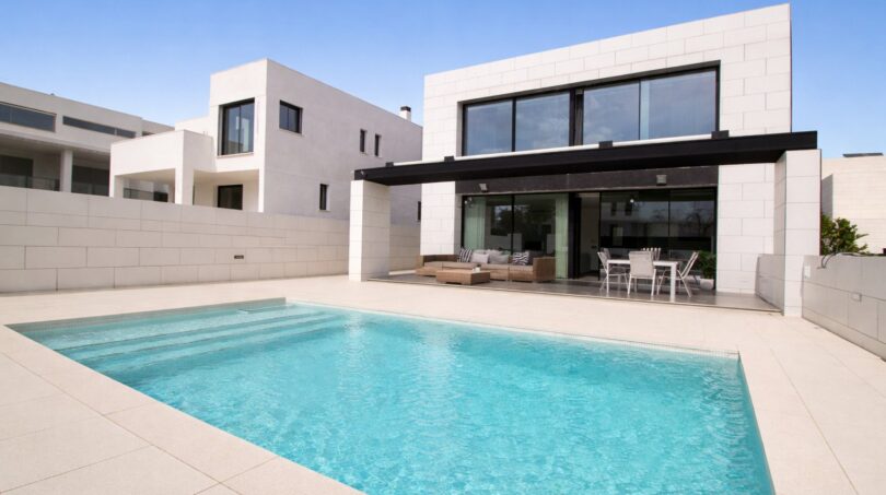 Modernes Einfamilienhaus in Palma de Mallorca mit türkisblauem Pool und überdachter Terrasse mit Loungebereich.
