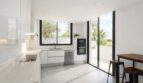 Moderne weiße Küche mit Kochinsel, Edelstahlgeräten und Schiebetür zur Terrasse in Palma