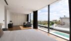 Helles Schlafzimmer mit Parkettboden, Panoramaverglasung und Blick auf Pool und Landschaft in Palma de Mallorca.