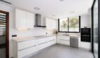 Moderne weiße Einbauküche mit Kochinsel, Induktionsherd und Edelstahlgeräten im Einfamilienhaus Palma de Mallorca