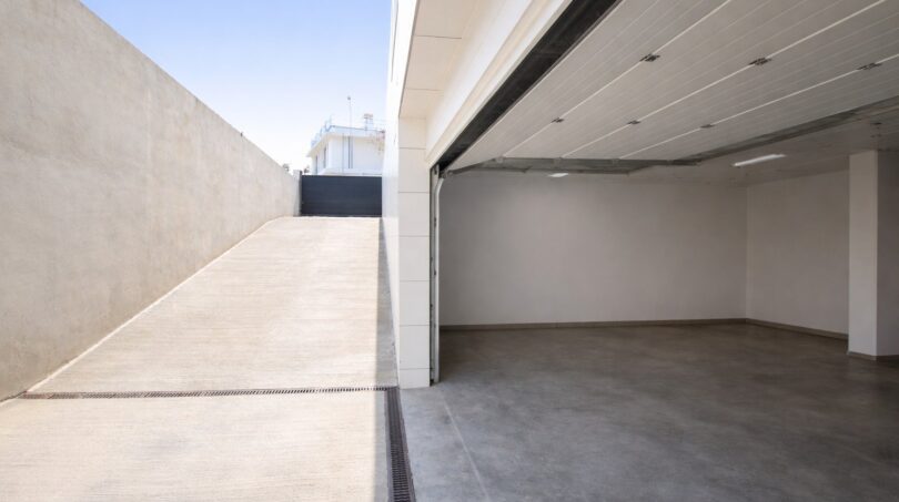 Leere Doppelgarage mit Betonboden und Einfahrtsrampe eines modernen Einfamilienhauses in Palma de Mallorca.