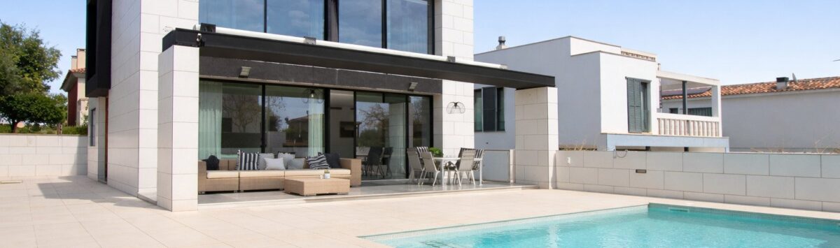 Moderne Villa in Palma de Mallorca mit Pool, Terrasse und großen Glasfronten unter blauem Himmel.