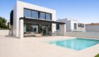 Moderne Villa in Palma de Mallorca mit Pool, Terrasse und großen Glasfronten unter blauem Himmel.