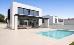 Modern villa in Palma de Mallorca with pool, terrace and large glass fronts under blue sky.