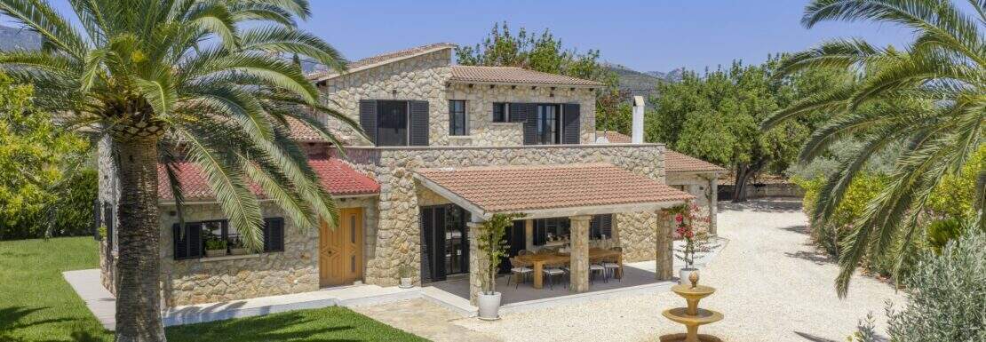 Luxusfinca Binissalem: Natursteinvilla mit Terrassenpavillon, Springbrunnen und Palmen im sonnigen Innenhof.