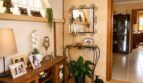 Eleganter Eingangsbereich mit Natursteinwand, Schmiedeeisen-Spiegel, Holzkommode und Familienfotos in Landhaus Sencelles.
