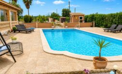 Privater Pool mit Sonnenliegen und Palmen der Finca in Sencelles unter blauem Himmel.