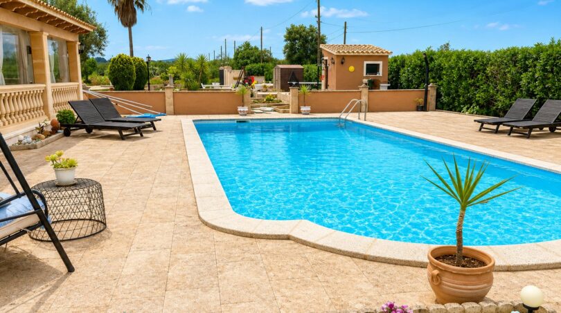 Privater Pool mit Sonnenliegen und Palmen der Finca in Sencelles, umgeben von mediterranem Grün.