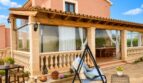 Sonnige Terrasse mit Schaukelsessel, Pool und überdachtem Essbereich einer Landfinca in Sencelles.