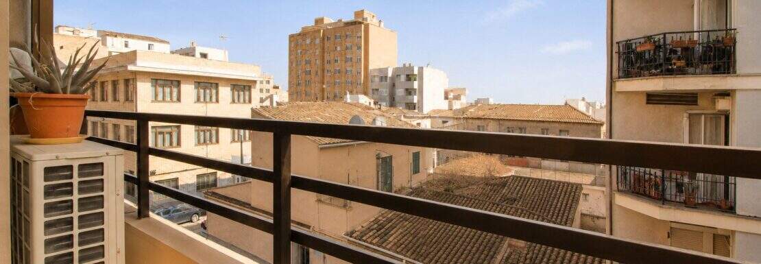 Balkon der 3-Zimmer-Wohnung in Palma mit Stadtblick, schwarzem Geländer, Klimaanlage und Topfpflanze