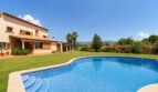 Außenansicht der Finca in Marratxí mit geschwungenem Pool, gepflegtem Rasen und mediterraner Architektur.